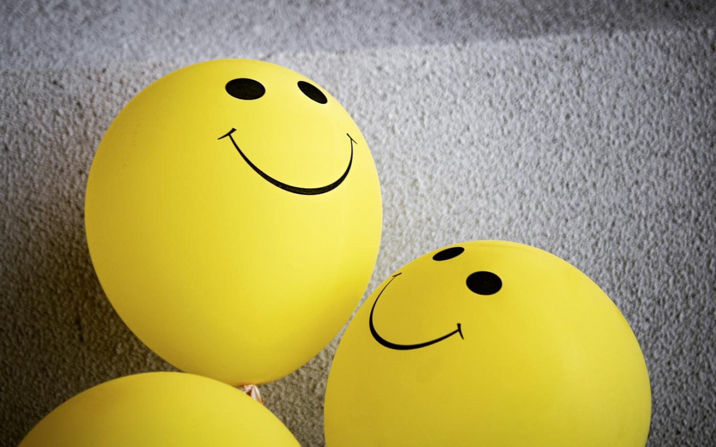 Two yellow balloons with smiley faces on them