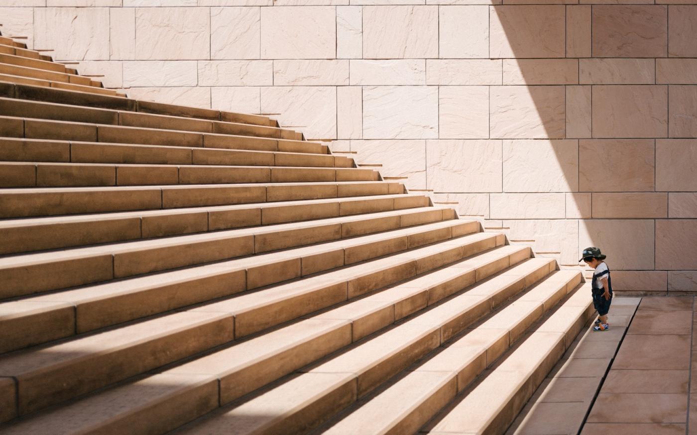 Toddler standing at the bottom of a stone staircase