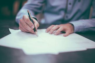 man writing on paper by Scott Graham courtesy of Unsplash.